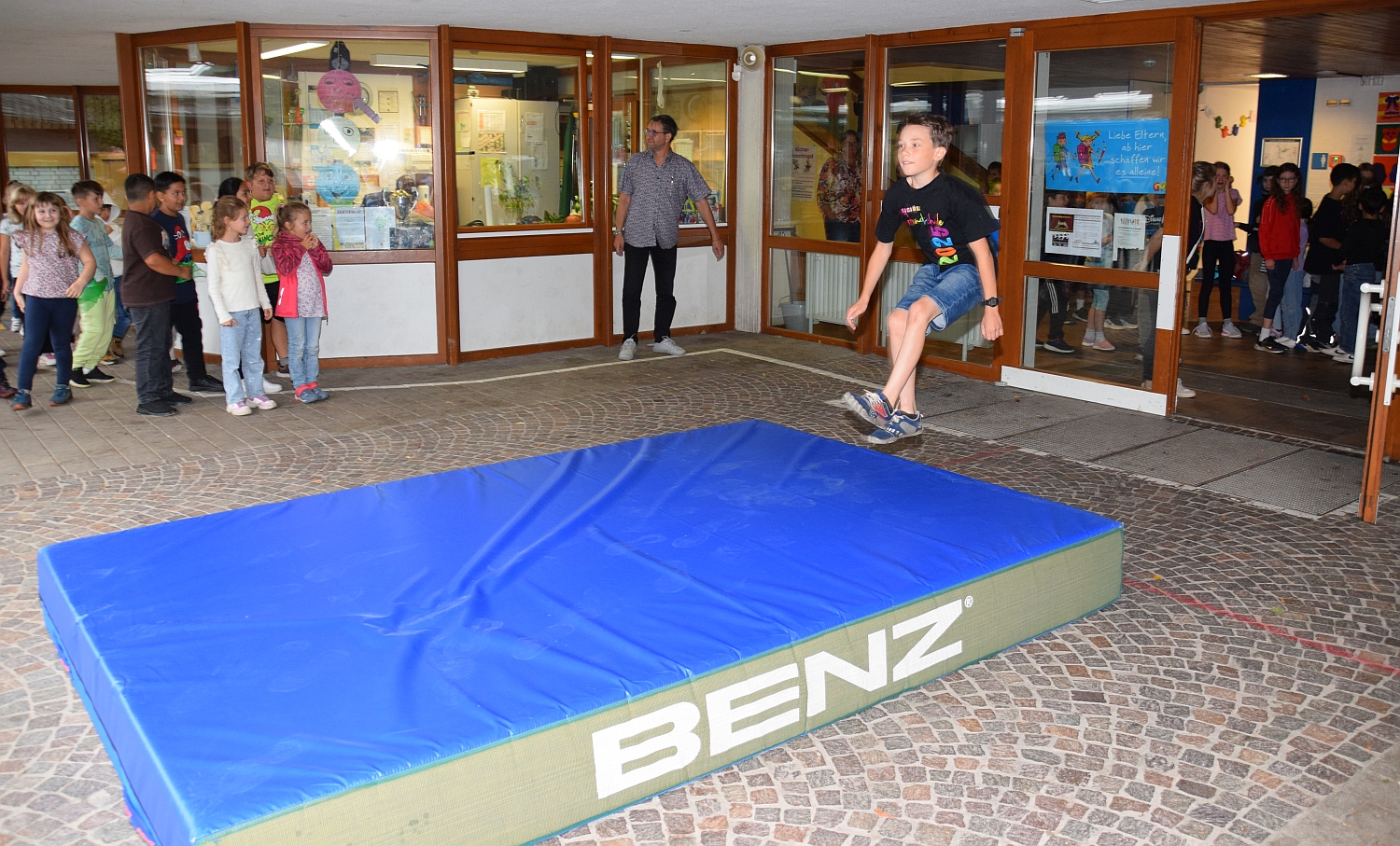 Viertklässler springt aus der Türe heraus auf eine Weichbodenmatte